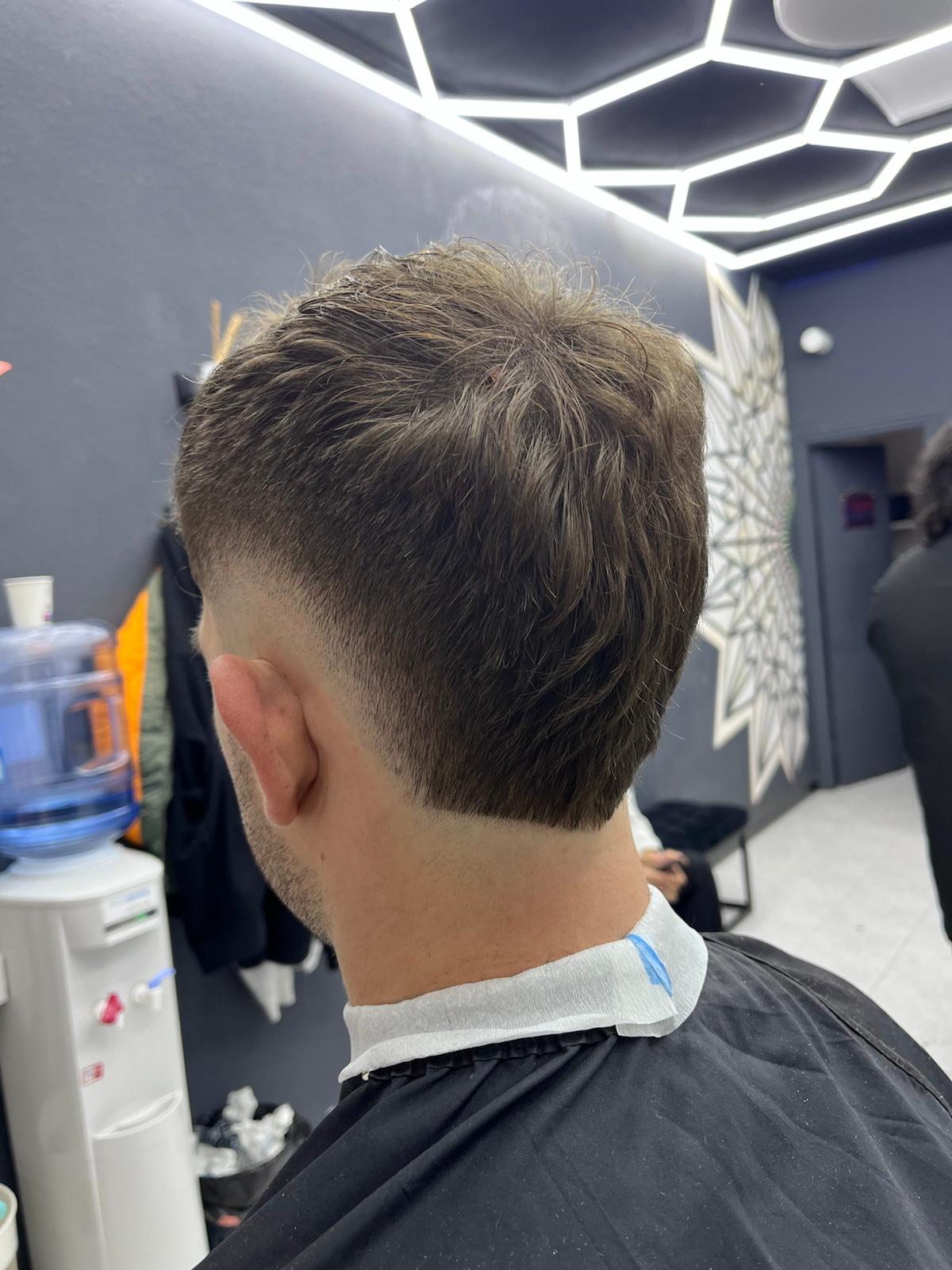 Corte degradado con moño alto y barba arreglada